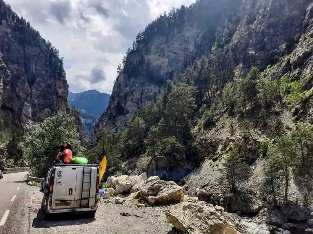 Van with kayaks on roof in laybye by river